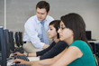 © moodboard - Professor assisting female students in computer lab