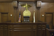 Legal Scales With Flags Behind Judge's Chair In Courtroom