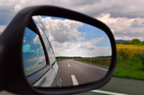 Fototapeta Dmuchawce - Traveling, rear view mirror road view and clouds