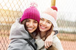 © BigLike Images - Two female best friends in knit beanies and coats hugging and smiling