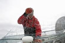 Fisherman Detangling Fishing Net On Boat