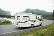 Recreational vehicle passing through a lakeside road with mountain in background, Alaska, USA
