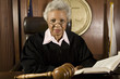 Portrait of a senior female judge with book in courtroom