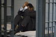 Distraught businessman sitting on bed in prison cell