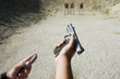 © moodboard - Closeup of man's hand loading hand gun at firing range