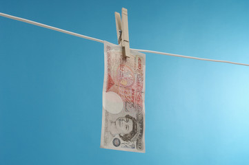 British paper currency on clothesline against blue background