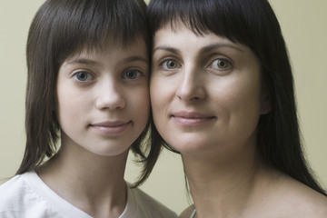 Closeup portrait of a mother and daughter against colored background