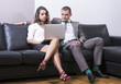 © Addoro - Happy couple sitting on a sofa together using  a laptop.