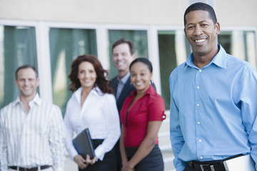 Wall Mural - Portrait of an African American businessman with multiethnic executives in the background