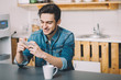 © alexshutter95 - Young man sitting at a table in the kitchen with his mobile phone