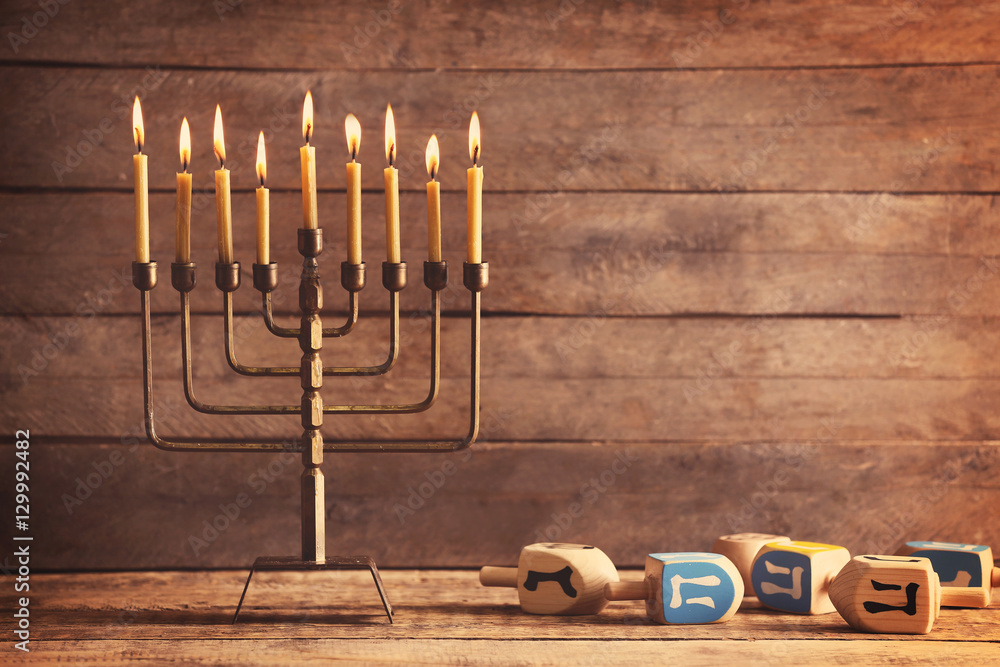 Menorah with candles for Hanukkah on table against wooden background
