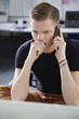 © MDBPIXS - Serious young man looking at laptop while using cell phone in office