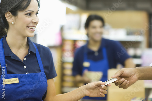 Cuadros en Lienzo Closeup of a hand giving female employee loyalty card in supermarket