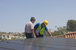 © moodboard - Maintenance workers inspecting solar panels on rooftop