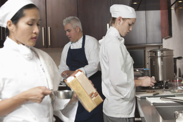 Wall Mural - Three chefs working together in busy commercial kitchen