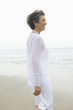 © MDBPIXS - Side view of a woman in casual white wear looking away while standing at beach