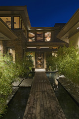 Exterior of two storey house with wooden walkway over water