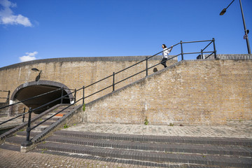 Wall Mural - Side view of young woman walking down stairs against blue sky