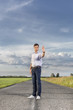 © MDBPIXS - Full length of serious young man holding up hand to stop at country road