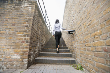 Wall Mural - Rear view of young businesswoman walking up stairs