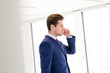 © MDBPIXS - Side view of young businessman using mobile phone in new office