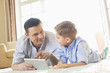 © moodboard - Father and son using digital table on floor at home