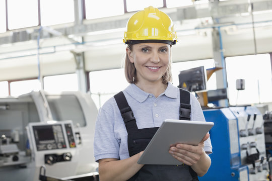 Portrait of smiling female worker using digital tablet in manufacturing industry