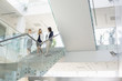 © moodboard - Businesswomen conversing while moving down steps in office