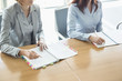 © MDBPIXS - Midsection of businesswomen with books at table in office