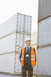 © moodboard - Middle-aged man standing against cargo containers in shipping yard