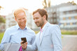© moodboard - Happy businessmen using mobile phone in city