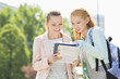 © MDBPIXS - Happy young female students reading book at college campus