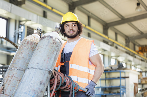 Fotografía Young manual worker moving gas cylinders in metal industry
