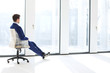 © MDBPIXS - Full length side view of thoughtful young businessman sitting on chair by windows in new office