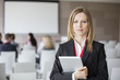 © MDBPIXS - Portrait of confident businesswoman holding digital tablet in seminar hall