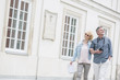 © MDBPIXS - Happy middle-aged tourist couple walking arm in arm by building
