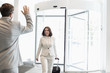 © MDBPIXS - Happy businesswoman with luggage walking towards male colleague in convention center