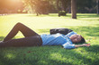 © Johnstocker - Young hipster woman lying down on grass.