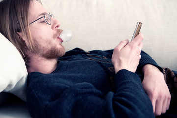 red-haired man lying on couch texting on phone