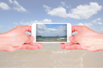 double exposure of man use two hand hold smart phone, tablet,cellphone, beach and sea view as communication and technology concept.