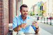 © baranq - Young man using digital tablet at outdoors cafe on city street