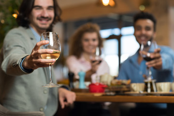 Wall Mural - Young Business People Group Drink Wine Sitting Restaurant Table, Friends Hold Glasses Toasting Smiling Mix Race Men Women