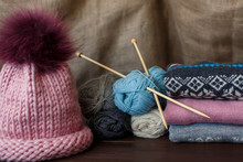 Knitting Homemade, Colorful Knitted Sweaters Near Pink Hat And Balls Of Yarn. Handmade Knitwear