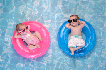 baby twin boy and girl floating on swim rings