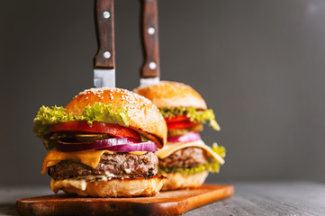 Two mouth-watering, delicious homemade burger used to chop beef. on the wooden table.