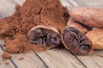 Cocoa beans and powder on wooden plank.