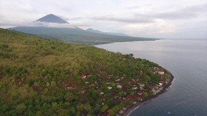 Wall Mural - Aerial shoot of calm lagoon with buildings on the shore and volcano on the horizon. Bali, Indonesia