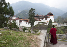 Buddhist Monk Looking Back At Trongsa Dzong, Bhutan's Largest Monastery Fortress Established In 1543 Above Mangde River Gorge, Bhutan