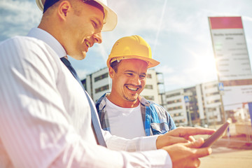 Canvas Print - happy builders in hardhats with tablet pc outdoors