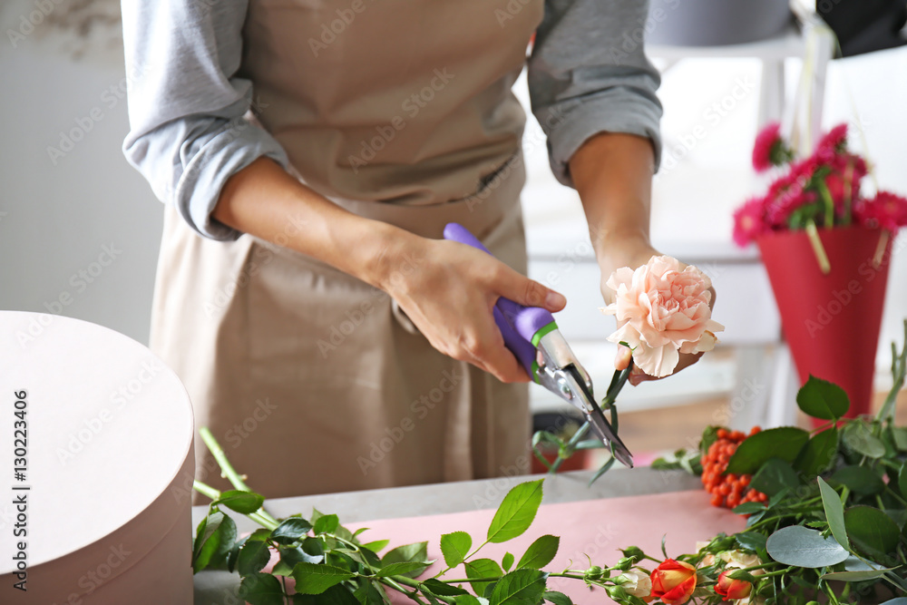 Female florist hands making composition with flowers closeup